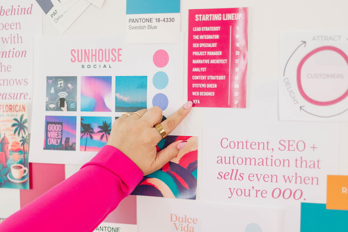 A hand points to a bright pink starting lineup card on a colorful brand mood board filled with social media graphics, color palettes, and marketing visuals. The scene suggests a creative strategy session highlighting how an outdated website can be refreshed with cohesive branding, content, and SEO that supports business growth.