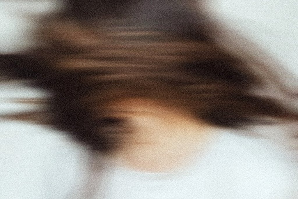 A blurred close up of a person with brown hair in motion creates a distorted unclear image. The visual conveys mental fog and overwhelm commonly experienced during entrepreneur burnout.